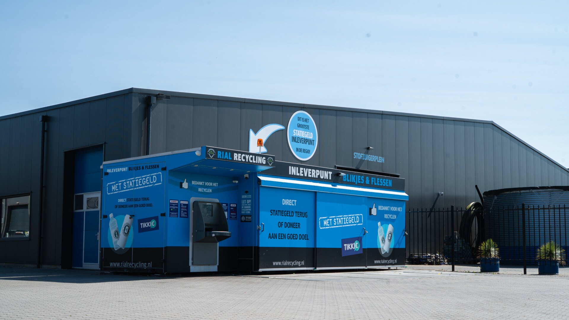 Het blauwe inleverpunt van Rial Recycling naast de gevel met STOFZUIGERPLEIN