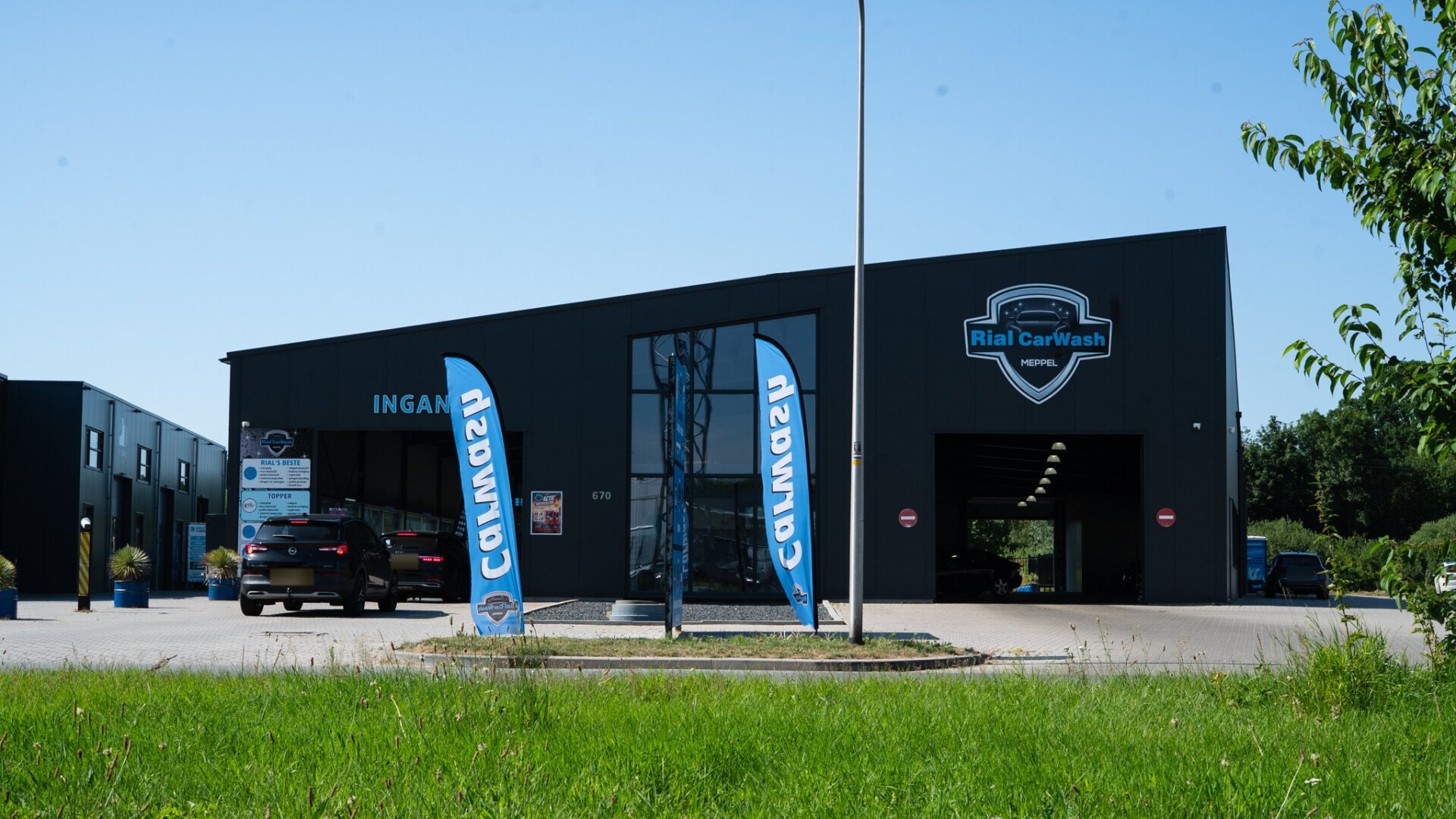 Het gebouw van Rial CarWash aan de Blankenstein, met de blauwe CarWash-vlaggen en de open uitgang